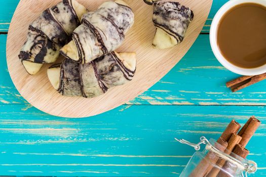 Croissant pastry with cup of coffee on vintage wooden background.