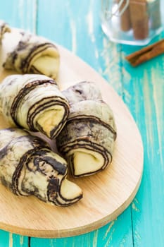 Croissant bread with cinnamon on blue wooden background.