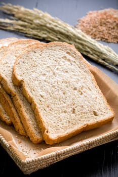 Slices of whole wheat bread in basket on black background.