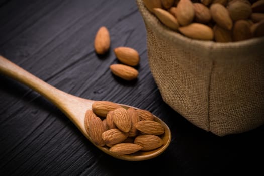 Almond in sack on black wooden table.