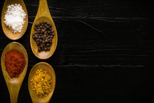 Various kinds of spice in wooden spoon background.
