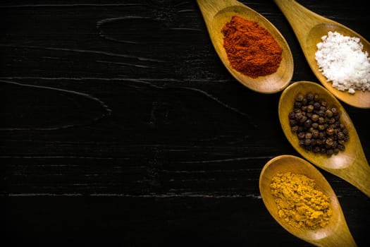 Various kinds of spice in wooden spoon background.