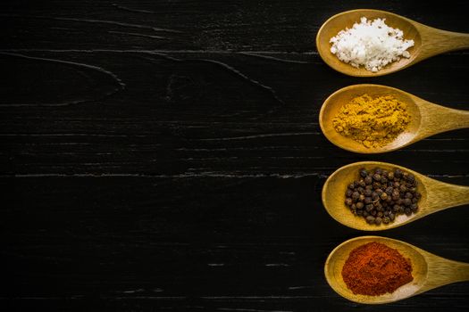 Various kinds of spice in wooden spoon background.