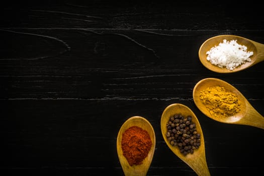 Various kinds of spice in wooden spoon background.