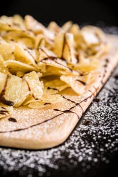 Banana chips with icing sugar and chocolate sauce.