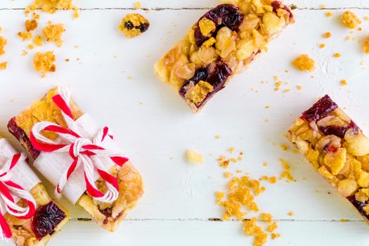 Muesli or granola bars with cranberry on white wooden background.