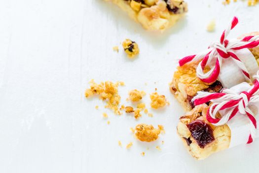 Muesli or granola bars with cranberry on white wooden background.