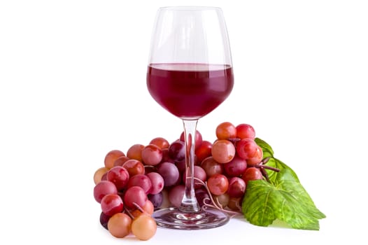 Red wine in a glass with grape bunch.