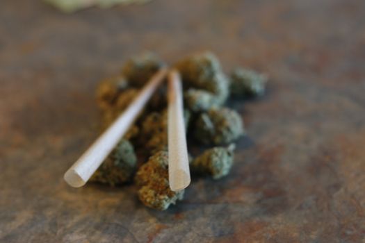 closeup of dried marijuana and handmade cigarette in ashtray