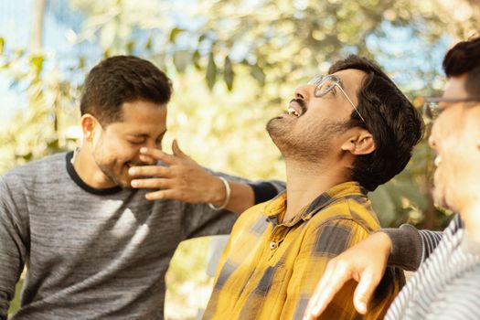 Three young adult laughing and having fun at picnic - Concept of happy friendship - youthful Male friends socializing at college