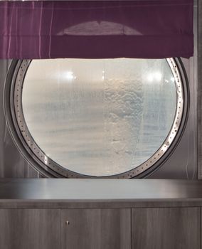 Round porthole of a sea cruise ship with water jets outside. Concept of sea travel.