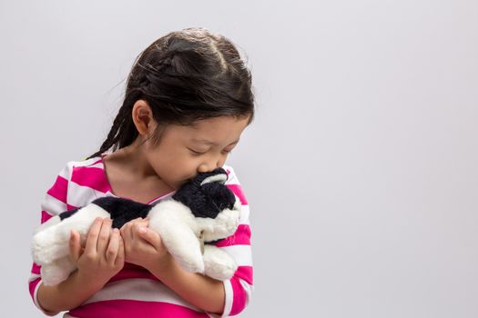 Young girl holding kitten doll in her arms.