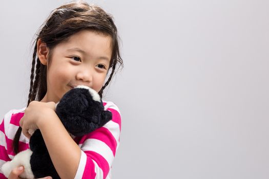 Young girl holding kitten doll in her arms.