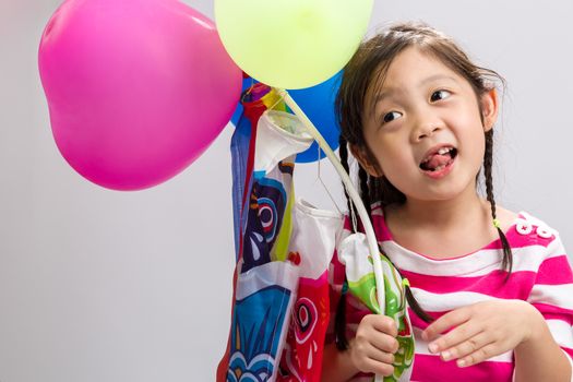 Child holding colorful balloons on white background.