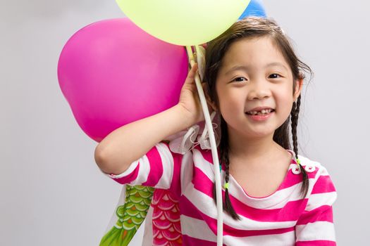 Child holding colorful balloons on white background.