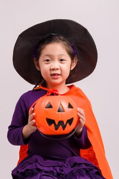 Child in Halloween costume with big pumpkin.