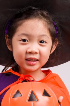 Child in Halloween costume with big pumpkin.