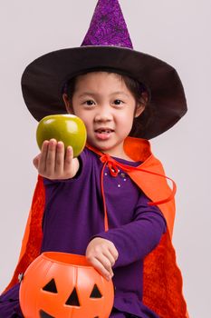 Child in Halloween costume with big pumpkin.