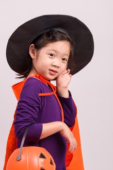 Child in Halloween costume with big pumpkin.