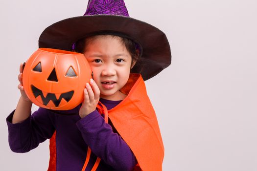 Child in Halloween costume with big pumpkin.