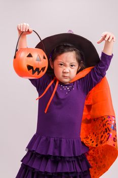 Child in Halloween costume with big pumpkin.