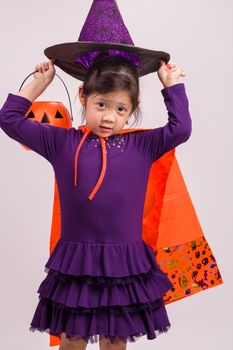 Child in Halloween costume with big pumpkin.