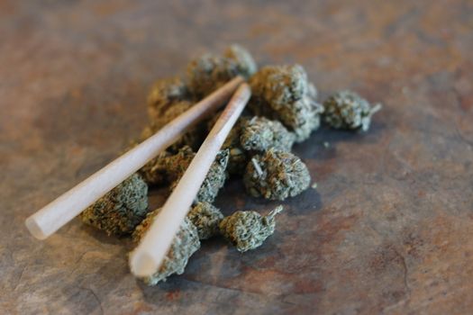 closeup of dried marijuana and handmade cigarette in ashtray