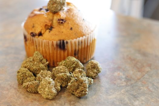A cannabis muffin next to a bunch of marijuana buds.