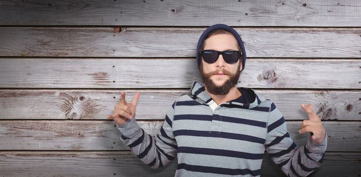 Hipster showing rock and roll hand sign against digitally generated grey wooden planks