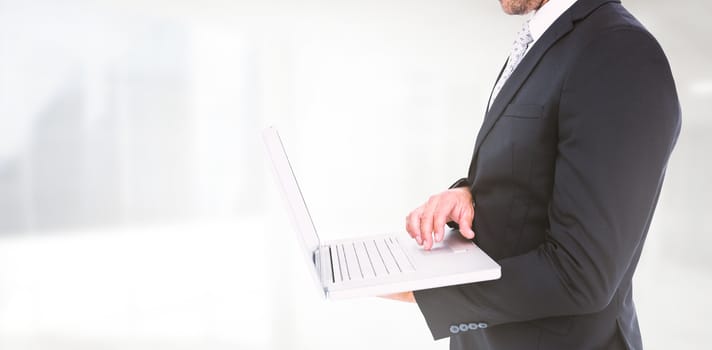 Businessman holding laptop against modern room overlooking city