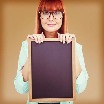 Smiling hipster woman holding blackboard against maroon background