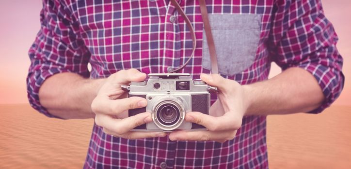 Mid section of man using camera against desert scene