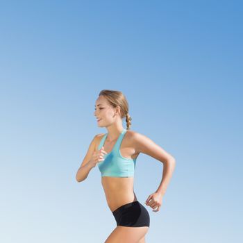 Fit woman jogging  against blue sky