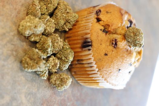 A cannabis muffin next to a bunch of marijuana buds.