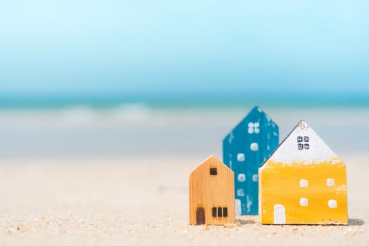 Model of a little house on sand with nature beach background. Dream life concept.