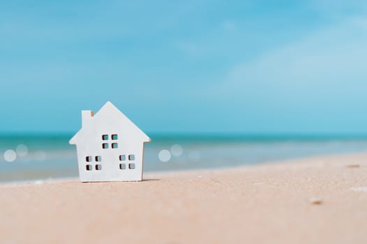 Model of a little house on sand with nature beach background. Dream life concept.