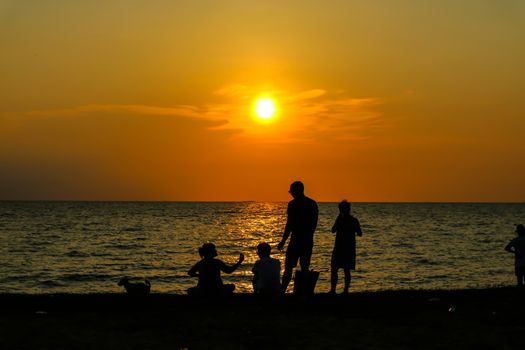 silhouette people family and pet playing at beach and sea sand sunset background