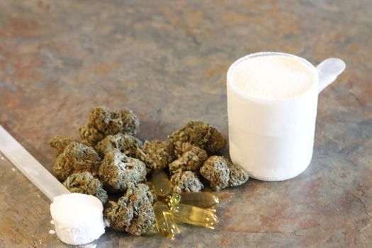 marijuana with various bodybuilding supplements on granite tabletop.