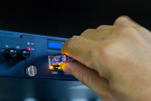 Hand of man holding The network cables to connect SFP module port in the Datacenter room, concept Communication technology