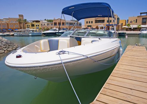 A luxury speedboat moored to a private jetty in a tropical marina