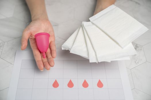 The choice between menstrual cup and sanitary napkin on woman hand.