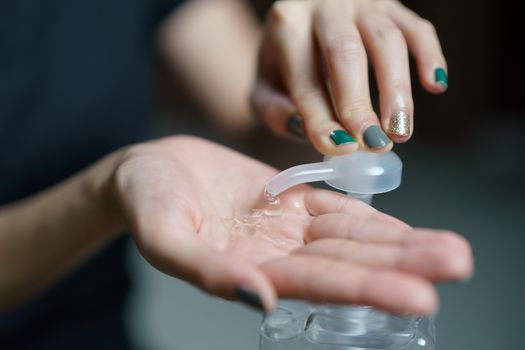 hands using wash hand sanitizer gel pump dispenser. Clear sanitizer in pump bottle, for killing germs, bacteria and virus.