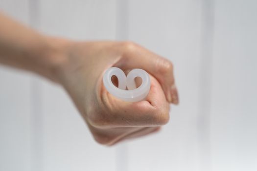 Woman hands folding a menstrual silicone cup.