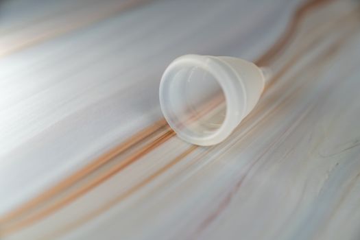 Menstrual cup on a white marble background.