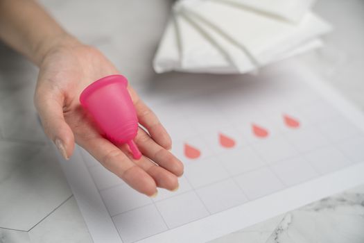 The choice between menstrual cup and sanitary napkin on woman hand.