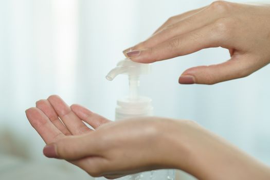 Female hands using wash hand sanitizer gel pump dispenser. Clear sanitizer in pump bottle, for killing germs, bacteria and virus.