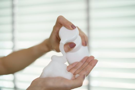 Woman hands pump liquid soap into palm for washing hands. For killing germs, bacteria and virus.