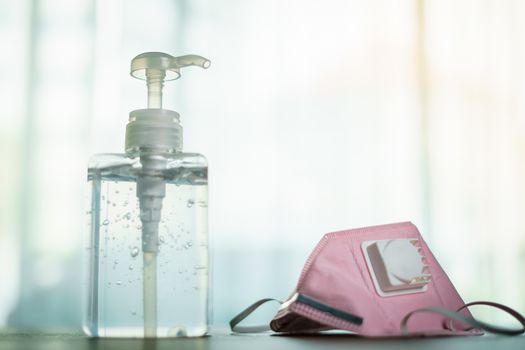 Antibacterial transparent hand sanitizer gel in a plastic bottle with surgical mask.