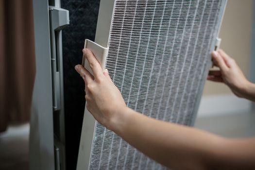 Woman hand open air purifier for clean dirty air purifier HEPA filter.