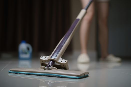 Woman using a flat wet-mop cleaning floor in the house. protect virus covid-19